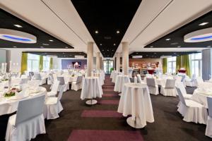 une salle de banquet avec des tables blanches et des chaises blanches dans l'établissement Riverside Hotel, à Nordhorn