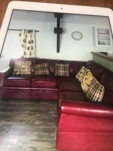 sala de estar con sofá rojo y reloj en Woodland Cottage en Faux-la-Montagne