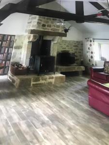 uma sala de estar com uma lareira de pedra e um sofá vermelho em Woodland Cottage em Faux-la-Montagne