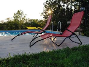 duas cadeiras vermelhas sentadas ao lado de uma piscina em Il carpino bianco em Puegnago