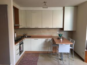 a kitchen with white cabinets and a table and chairs at La vista sulla Valmalenco in Lanzada