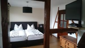 Schlafzimmer mit einem Bett mit weißen Kissen und einem TV in der Unterkunft Mario's fachwerkhaus am Huy in Schlanstedt
