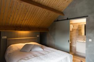 Schlafzimmer mit einem Bett mit Holzdecke in der Unterkunft Abeellogies in Tielt