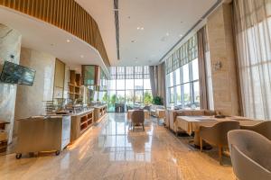 a restaurant with tables and chairs and large windows at Qilian Pearl Hotel Zhangye in Zhangye