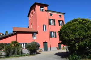 un bâtiment rouge avec un arbre devant lui dans l'établissement Ca Rossa vicino al mare nuova e pulita, à Diano Marina