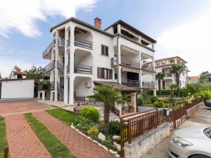 a white house with a fence in front of it at Apartments Špadići in Poreč