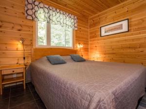 ein Schlafzimmer mit einem Bett in einem Blockhaus in der Unterkunft Holiday Home Metsäpirtti by Interhome in Saukkokoski