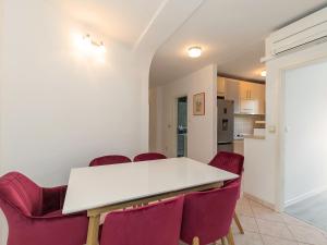 a dining room with a white table and red chairs at Apartments Špadići in Poreč