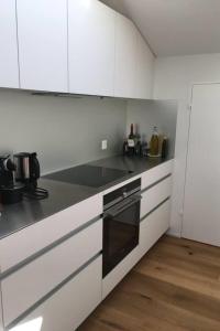 una cucina con armadi bianchi e un forno a piano cottura nero di Apartment Turmalin 2- Stock by Interhome a Lenk