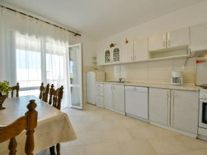 a kitchen with white cabinets and a table and a window at Holiday Home Mia by Interhome in Anić