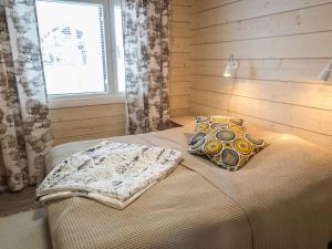 ein Schlafzimmer mit einem Bett mit Kissen und einem Fenster in der Unterkunft Holiday Home Äkäsmartti a by Interhome in Äkäslompolo