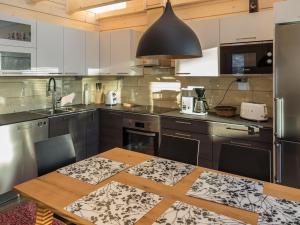 eine Küche mit einem Holztisch und einer schwarzen Pendelleuchte in der Unterkunft Holiday Home Äkäsmartti a by Interhome in Äkäslompolo