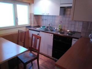 eine Küche mit einem Herd, einer Spüle und einem Tisch in der Unterkunft Apartment Sattelboden 4 by Interhome in Engelberg