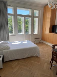 a bedroom with a large white bed and some windows at Le Relais de l'Orangerie in Strasbourg