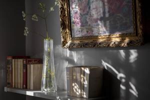 a table with a vase and books on a shelf at Maison d'Hôtes La Singulière in Sévérac-le-Château
