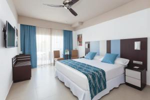 a bedroom with a large white bed with blue pillows at Hotel Riu Costa del Sol - All Inclusive in Torremolinos