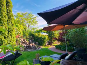 eine Terrasse mit einem Sonnenschirm und Stühlen sowie einen Garten in der Unterkunft Uma Rosa in Lüneburg