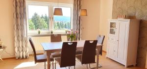comedor con mesa, sillas y ventana en Moderne Ferienwohnung mit eigenem Garten und traumhaften Blick, en Wilhelmsthal