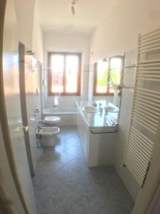 bagno bianco con 2 lavandini e servizi igienici di Casa Vacanze Magnolia a Borgo Ticino