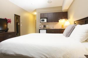 a bedroom with a large white bed and a kitchen at Radisson Hotel Fort St John in Fort Saint John