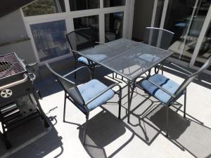 a glass table and chairs on a patio with a grill at Free Terrace in Piran