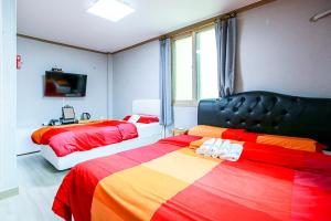 two beds in a bedroom with red and yellow at K Guesthouse in Gangneung