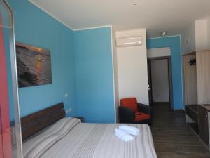 une chambre d'hôtel avec un lit et un fauteuil rouge dans l'établissement ChrisMare Hotel, à Mazzeo