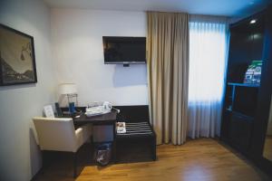 a room with a desk with a chair and a window at Enjoy 1313AG Hotel Touring in Chiasso