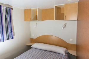 Habitación pequeña con cama y armarios de madera. en Camping Las Gaviotas, en Naveces