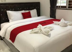 a large white bed with red and white sheets at RedDoorz near CitraLand Gama City Medan in Pulauberayan Dadap
