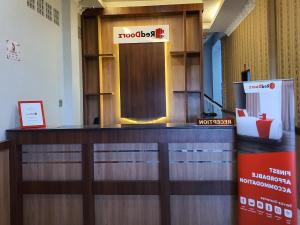 a reception desk in a lobby with a wooden door at RedDoorz near CitraLand Gama City Medan in Pulauberayan Dadap