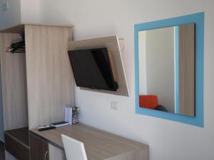 a tv on a wall next to a mirror at ChrisMare Hotel in Mazzeo