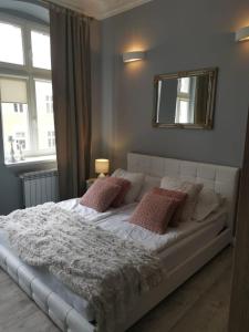 a bedroom with a white bed with pillows and a mirror at Apartamenty Apartlux in Poznań
