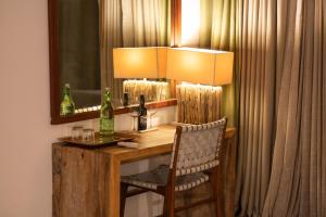 a table with a lamp and a chair and a mirror at Kaav Safari Lodge, Kabini in Begūr