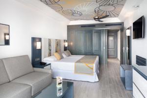 a hotel room with a bed and a couch at Riu Vistamar Gran Canaria - All Inclusive in Puerto Rico de Gran Canaria