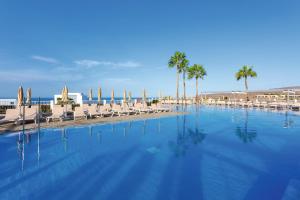 a large swimming pool with chairs and palm trees at Riu Vistamar Gran Canaria - All Inclusive in Puerto Rico de Gran Canaria