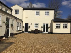 a large white house with a gravel driveway at Courtyard Cottage - Great Paxton in Saint Neots