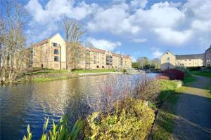a large building next to a river with buildings at River Ground Floor Apartment - 70 Skipper Way in Saint Neots