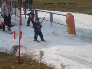 dwójka dzieci bawi się w śniegu na nartach w obiekcie Casa Spel Mir w mieście Disentis