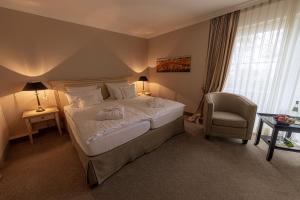 a bedroom with a large bed and a chair at Strandhotel Fontana in Timmendorfer Strand
