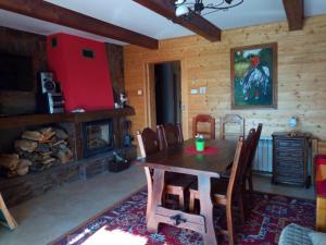 a dining room with a table and a fireplace at Świerkowe Chatki - Apartament Kominkowy in Olchowiec