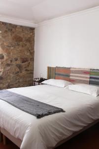 ein Schlafzimmer mit einem großen weißen Bett und einer Steinmauer in der Unterkunft Casa de Campo Alter Pedroso in Alter do Chão