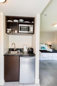 a kitchen with a sink and a microwave and a bed at Luxury Lakeside Studio in Queenstown