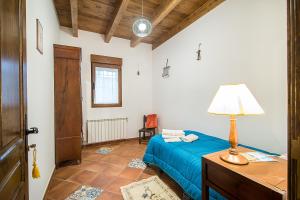 1 dormitorio con cama azul y mesa con lámpara en Casa Rural LAS ABUBILLAS en Mirabueno