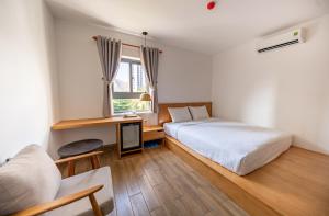 a bedroom with a bed and a desk and a window at Coast House Boutique Hotel in Nha Trang