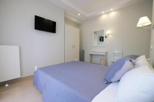 a white bedroom with a bed and a flat screen tv at Limnia Gi in Myrina