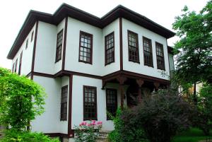 a white house with black windows and flowers at Mehves Hanim Konagi in Safranbolu