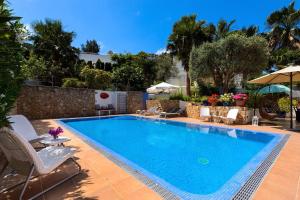 una piscina en un patio con sillas y sombrillas en Villa Blanca Santa Eulalia en Santa Eulalia del Río