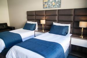 Habitación de hotel con 2 camas y almohadas azules en The Cato Suites Hotel, en Durban