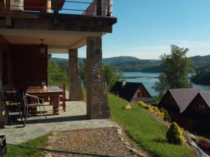 a patio with a table and a view of a lake at Świerkowe Chatki - Apartament Kominkowy in Olchowiec